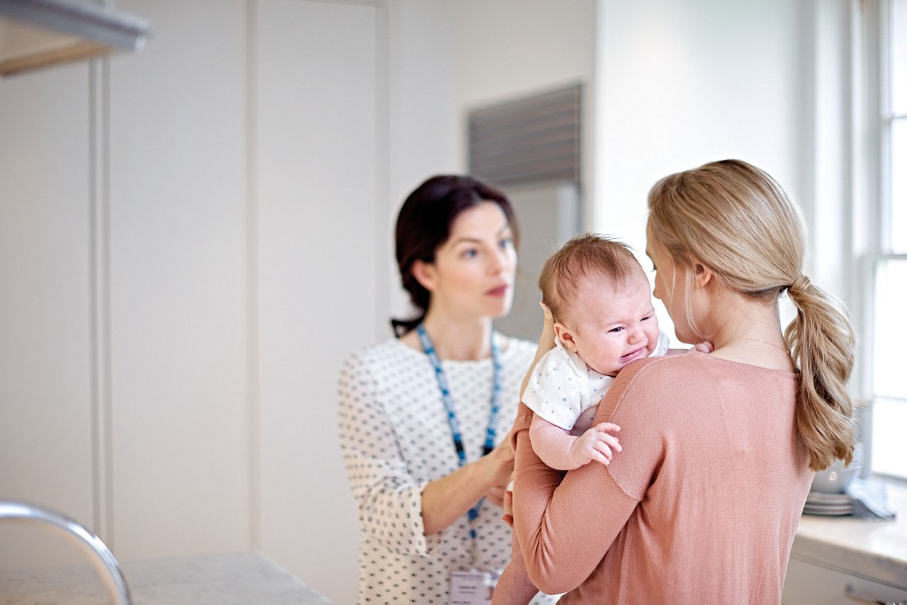 Mother holding a baby with colic at a GP appointment